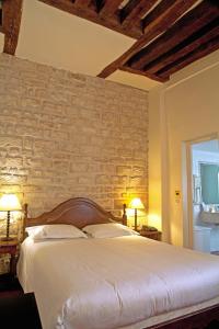 a bedroom with a large bed with a brick wall at Tonic Hôtel du Louvre in Paris