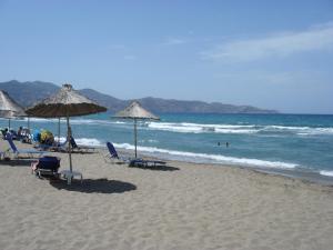 a beach with chairs and umbrellas and the ocean at La Santre Villa in Amoudara Herakliou