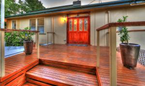 Casa con terraza de madera con puerta roja en Hillview Oak B&B, en Lankeys Creek