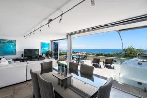 a dining room table with chairs and a large window at Picture Point Terraces in Noosa Heads