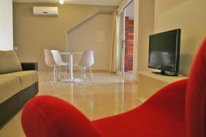 a living room with a table and chairs and a television at L' Escala Resort in L'Escala