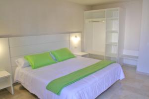 a bedroom with a large white bed with green pillows at L' Escala Resort in L'Escala +22 photos