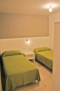 two beds in a room with green sheets at L' Escala Resort in L'Escala