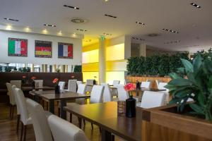 a restaurant with tables and white chairs and plants at relexa Hotel Ratingen City in Ratingen