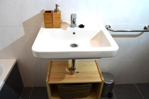 een badkamer met een witte wastafel op een houten standaard bij La Casa del Reloj Cadiz in Cádiz +26 foto's