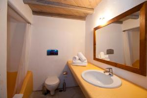 a bathroom with a sink and a mirror and a toilet at Nama Villas in Super Paradise Beach