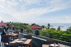 een man aan een tafel in een restaurant met uitzicht op de oceaan bij Sulis Beach Hotel & Spa in Kuta