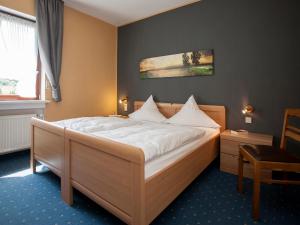 a bedroom with a bed and a chair at Pension Haus Brieden in Winterberg