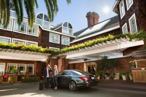 two people standing in front of a house with a car at The Stanford Park Hotel in Menlo Park