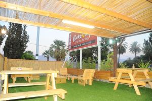 a group of picnic tables and benches in front of a restaurant at בקתה מקום טוב באמצע in Kinneret