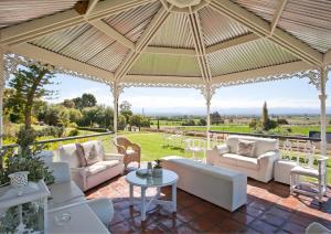 a pavilion with white furniture and a view of a field at La Plume Boutique Hotel & Spa in Oudtshoorn