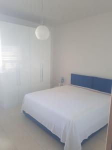 Schlafzimmer mit einem großen weißen Bett mit blauem Kopfteil in der Unterkunft Residenza Carone in Porto Cesareo