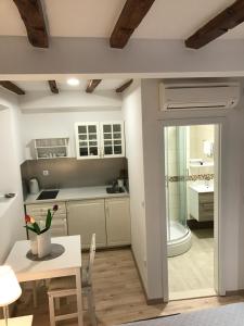a kitchen with white cabinets and a table and a bathroom at Rilati Old town Palace 2 in Dubrovnik