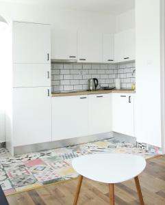 a kitchen with white cabinets and a table and a rug at Studio apartman in Zagreb