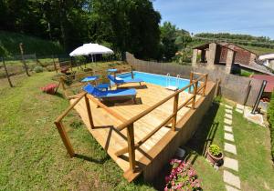 een houten terras met een zwembad en een parasol bij La Piccola Margherita in Capannori