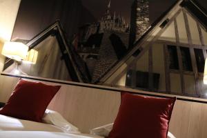 a bed with red pillows next to a window at Les Terrasses Poulard in Le Mont Saint Michel