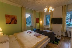 a bedroom with a large bed with chairs and windows at Pension Menge in Bad Schandau