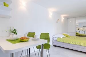 a bedroom with a bed and a white table and green chairs at Apartments Nikolina in Hvar
