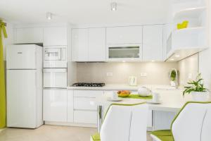 a white kitchen with white cabinets and a table and chairs at Apartments Nikolina in Hvar
