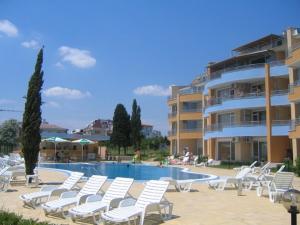 una piscina con sedie bianche e un edificio di Apartments Lucky Complex Ravda a Ravda