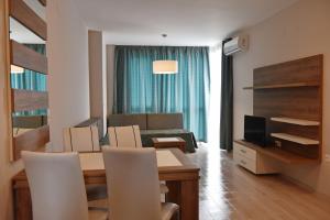 een woonkamer met een tafel, een bank en een televisie bij Apartments Lucky Complex Ravda in Ravda