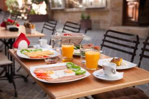 a wooden table with plates of food and glasses of orange juice at Consolato Boutique in Chania Town