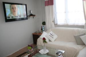 ein Wohnzimmer mit einem weißen Sofa und einem Flachbild-TV in der Unterkunft Apartament Centrum 3 pokojowy in Olsztyn