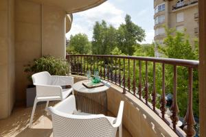 Un balcón con sillas blancas y una mesa. en Playa de Ondarreta 2 by FeelFree Rentals, en San Sebastián