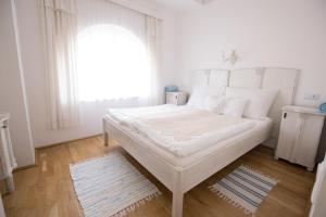 a white bedroom with a large bed and a window at Bacchus Apartman - Borbarlang, Badacsony in Badacsonytomaj