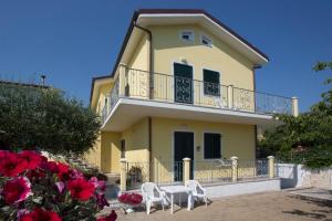 ein gelbes Haus mit zwei weißen Stühlen und einem Balkon in der Unterkunft Giglio Del Conero in Numana
