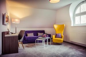 a living room with a purple couch and yellow chairs at Hotel am Rugard in Bergen auf Rügen