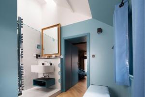 Zimmer mit blauen Wänden, einem Spiegel und einer Lampe in der Unterkunft Hotel Le Colombier Suites in Colmar