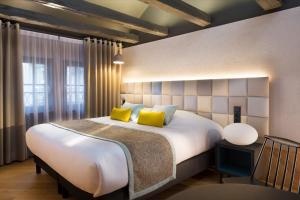 a bedroom with a large white bed with yellow pillows at Hotel Le Colombier Suites in Colmar