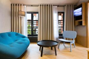 a living room with a blue couch and a chair at Hotel Le Colombier Suites in Colmar