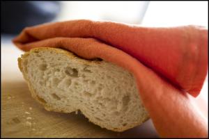 une personne tenant un morceau de pain sur une planche de découpe dans l'établissement Rooseboom22, à Aartrijke