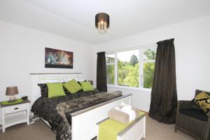 Un dormitorio con una cama con almohadas verdes y una ventana en Durie Vale Retreat en Whanganui