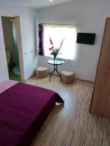 コンスタンツァにあるVila Arisaのベッドルーム1室(紫色のベッド1台、花のテーブル付)