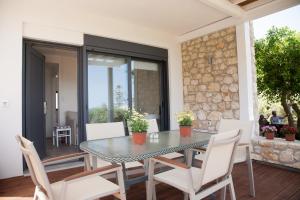 a dining room with a glass table and white chairs at Artemis Village Apartments & Studios in Stavros
