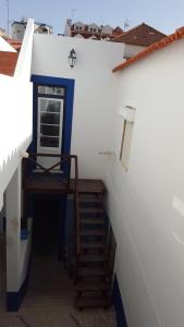 a stairway leading to a white building with a blue door at Casas da Villa - Quarto Privado in Ericeira