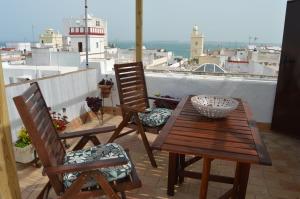 stół i dwa krzesła na balkonie z latarnią morską w obiekcie Apartamento El Mirador de Cadiz w Kadyksie