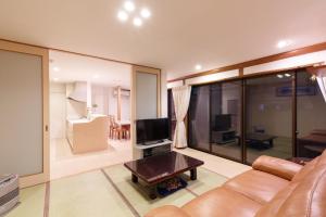 ein Wohnzimmer mit einem Sofa und einem TV in der Unterkunft Kanazawa Seiren Le Lotus Bleu in Kanazawa