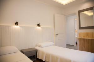 a white room with two beds and a mirror at Artemis Village Apartments & Studios in Stavros