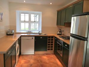a kitchen with green cabinets and a refrigerator at Dunnottar Woods Cottage in Stonehaven