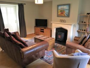 a living room with a couch and a fireplace at Dunnottar Woods House in Stonehaven