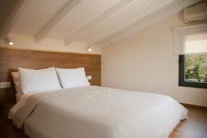 a bedroom with a white bed and a window at Artemis Village Apartments & Studios in Stavros