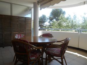 a porch with a wooden table and chairs and a window at Appartement Les Palmiers - Vacances Cote d'Azur in Cannes