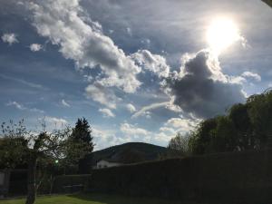 ein wolkiger Himmel mit der Sonne hinter einem Zaun in der Unterkunft Ferienwohnung Haus in Gladenbach