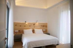 a bedroom with a white bed with a wooden headboard at Artemis Village Apartments & Studios in Stavros