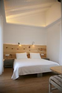 a bedroom with a large white bed with a wooden headboard at Artemis Village Apartments & Studios in Stavros