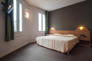 a bedroom with a bed and two windows at Hôtel Normandy in Fécamp